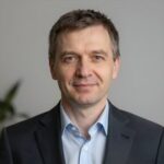 Портрет уверенного российского бизнесмена с дружелюбным взглядом на нейтральном размытом фоне в студии
